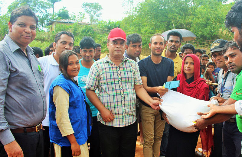 YPSA and WFP officials distributes rice bag to a female member of a Rohingya family
