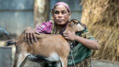 Woman with disability and her goat in front of her home in a village