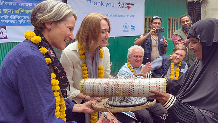 A woman handing over handicraft made by her to the visitors 