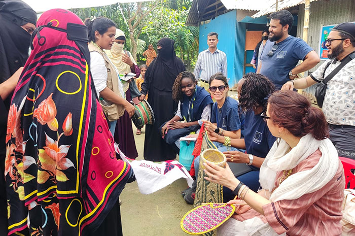 Visitor observing abd discussing handicraft made by women 