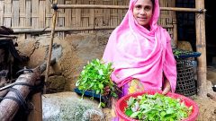 A woman beneficiary with vegetable in hand